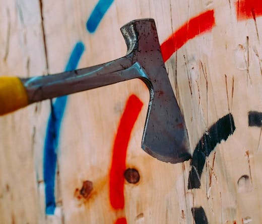 An axe wedged into a wooden wall target, from MANIAX, Sydney's axe throwing studio. 