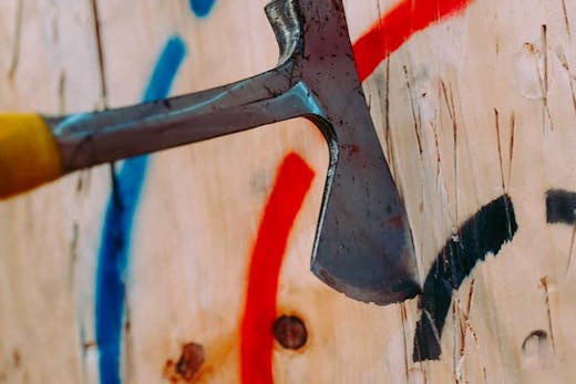 An axe wedged into a wooden wall target, from MANIAX, Sydney's axe throwing studio.