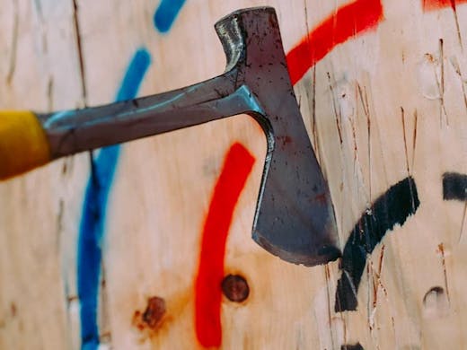 An axe wedged into a wooden wall target, from MANIAX, Sydney's axe throwing studio. 