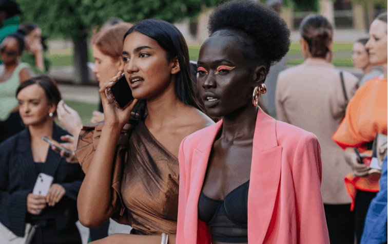 Two people dressed up with one talking on a phone. 