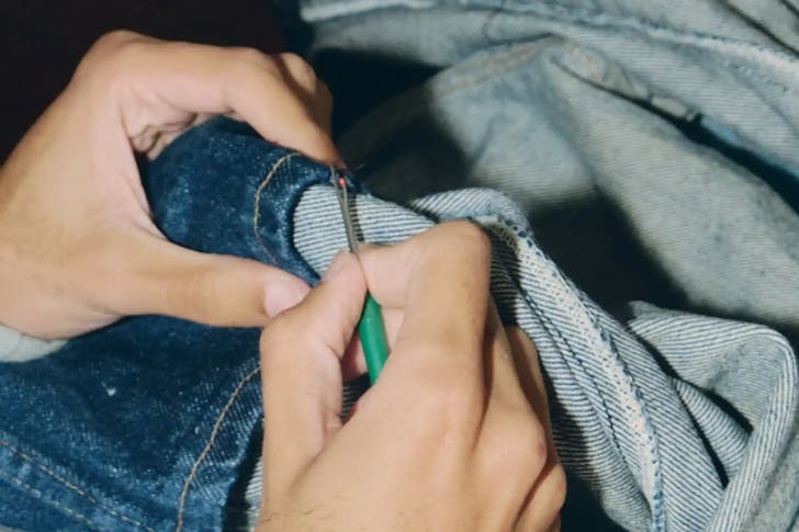 A closeup of someone stitching/sewing blue denim.