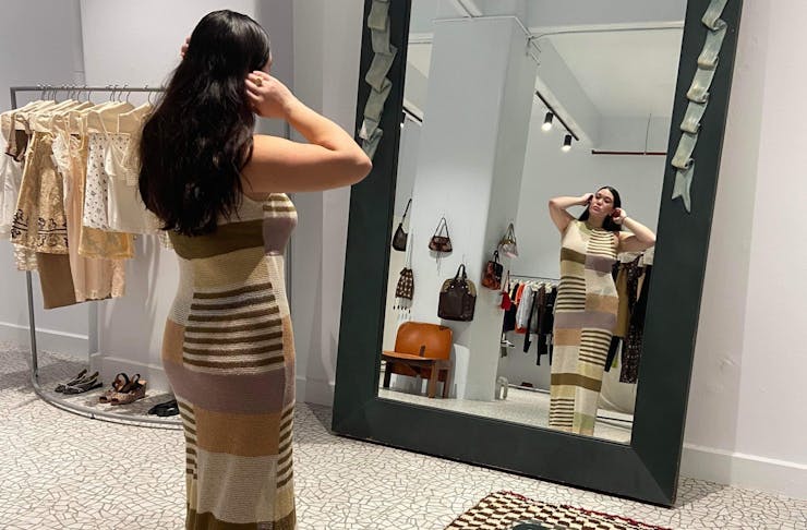 Woman standing in front of mirror trying on a dress