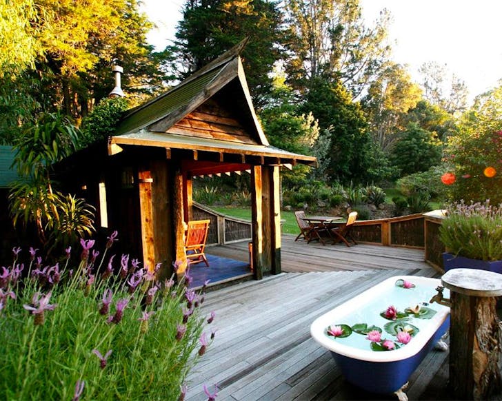A view of a gorgeous looking cottage with a bath with petals outside.