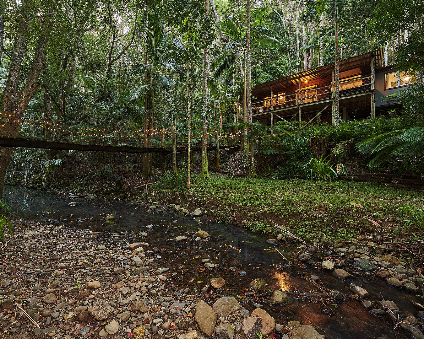 A fairy-lit bridge crosses to a cosy looking home.