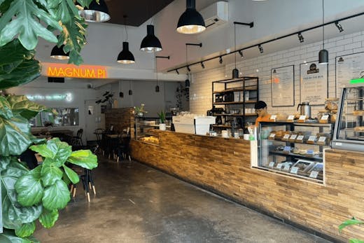 The inside of the store with plants and large wooden bar with a pie cabinet.