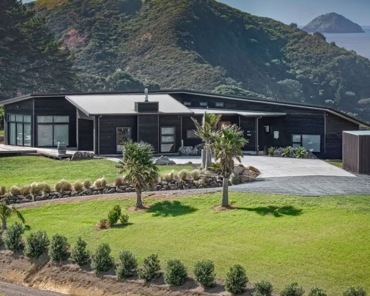 The exterior of Mahinepua Magic with an island in the background one of the best beach house Airbnbs in NZ