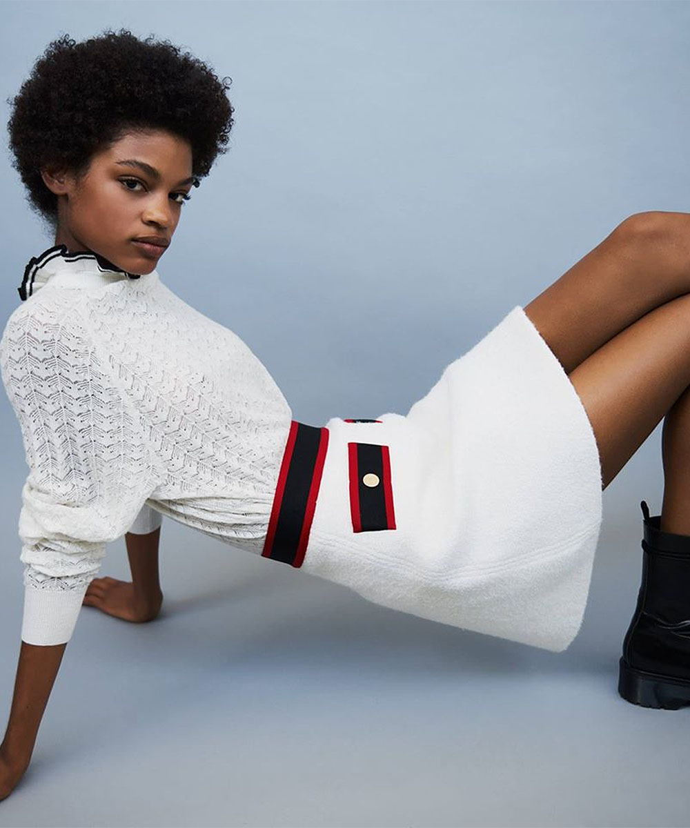 A model reclines wearing Maje clothing, a lovely little white ensemble.