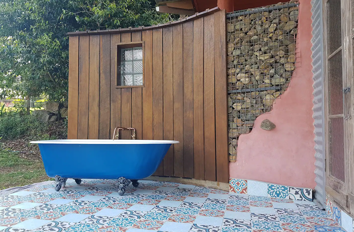 A blue outdoor bath sits near a pink wall at Cobhearthhome Cottage Airbnb one of the best accommodation options in Maleny