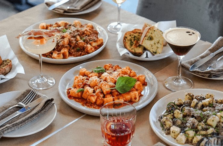 A table with three different plates of gnocchi.