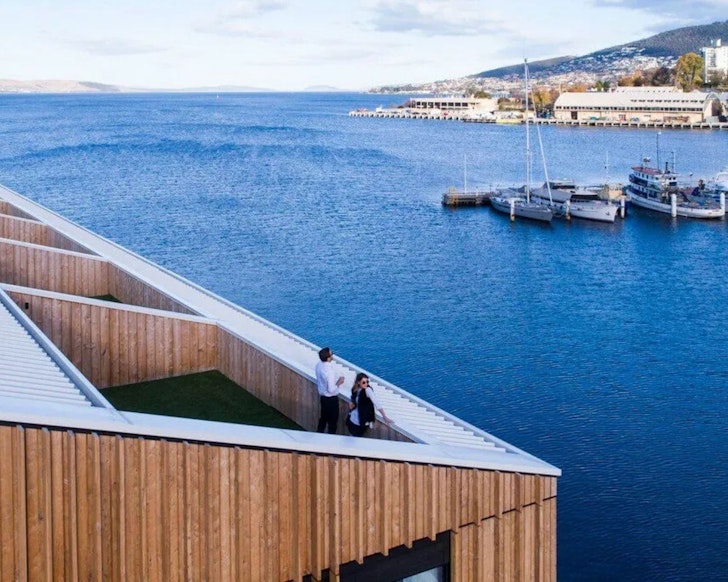 A couple looks out over the water from the terrace of a room at MACq 01 one of the best hotels in Australia