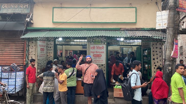 Man standing in crowd outside workshop.