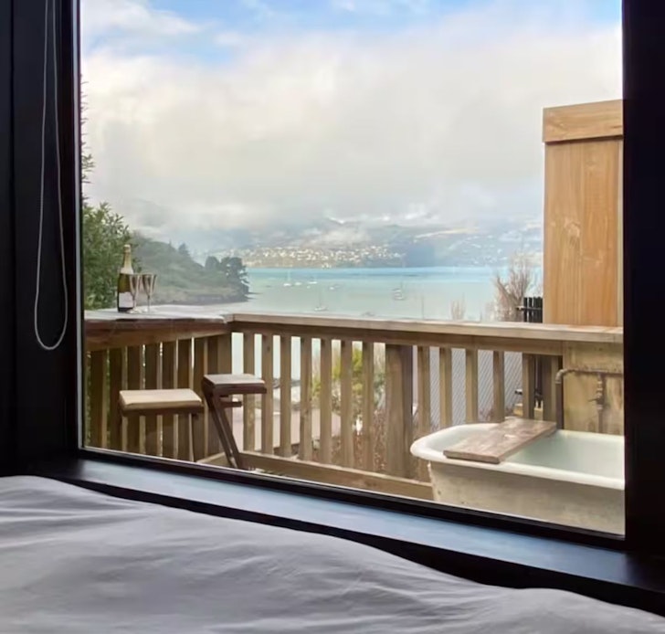 A view of the outdoor bath and water from Mariners Cabin romantic stay near Christchurch, New Zealand