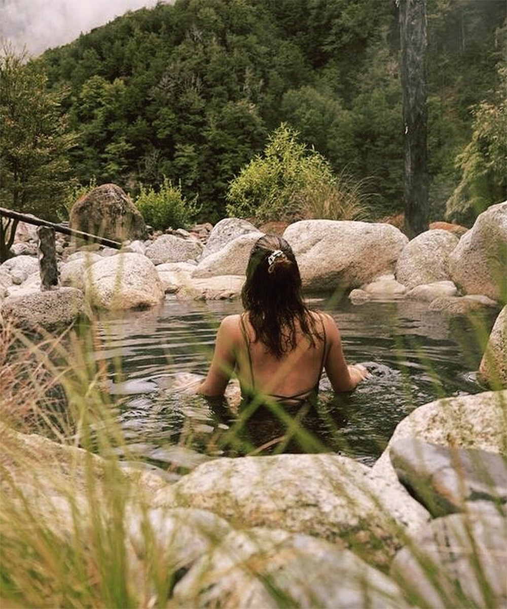 A girl sits in the water at Maruia Hot Springs