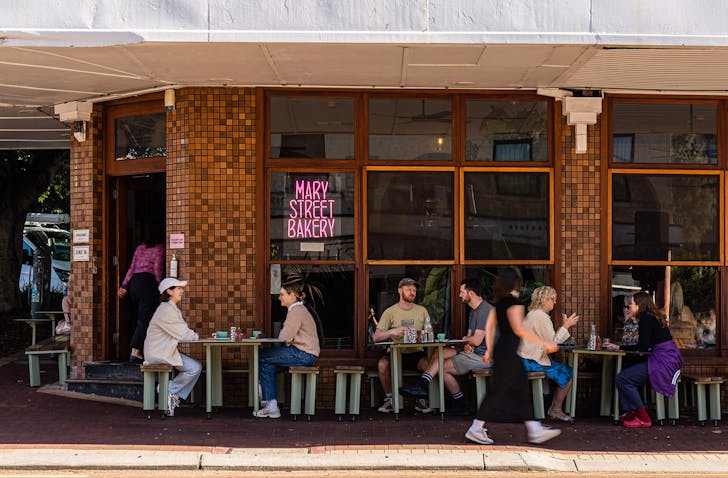 Several people are seated outside Mary Street Bakery drinking coffee.