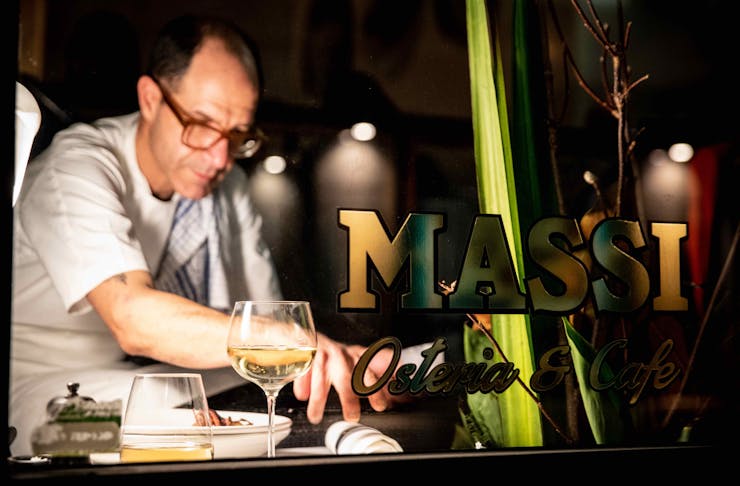 Chef/Owner Joe Vargetto plating up dishes at Massi with the restaurant sign in the forgeround 