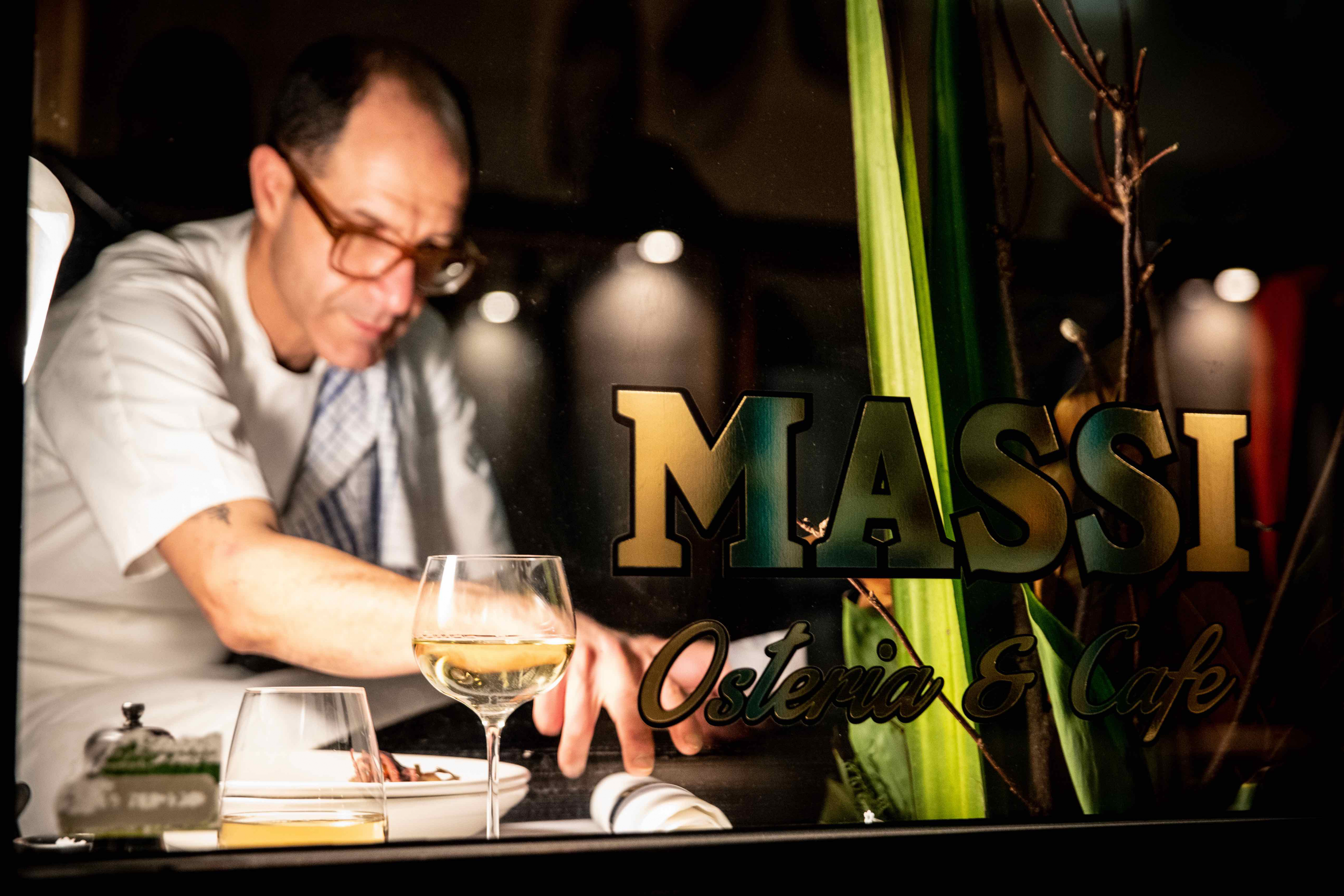 Chef/Owner Joe Vargetto plating up dishes at Massi with the restaurant sign in the forgeround 