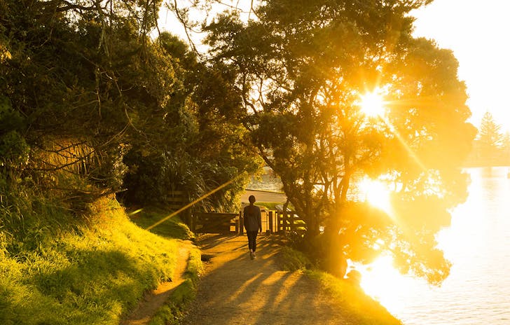 A girl walks around the base track at sunset, Mount Maunganui