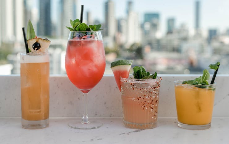 4 cocktails in a row on a bench overlooking the city.