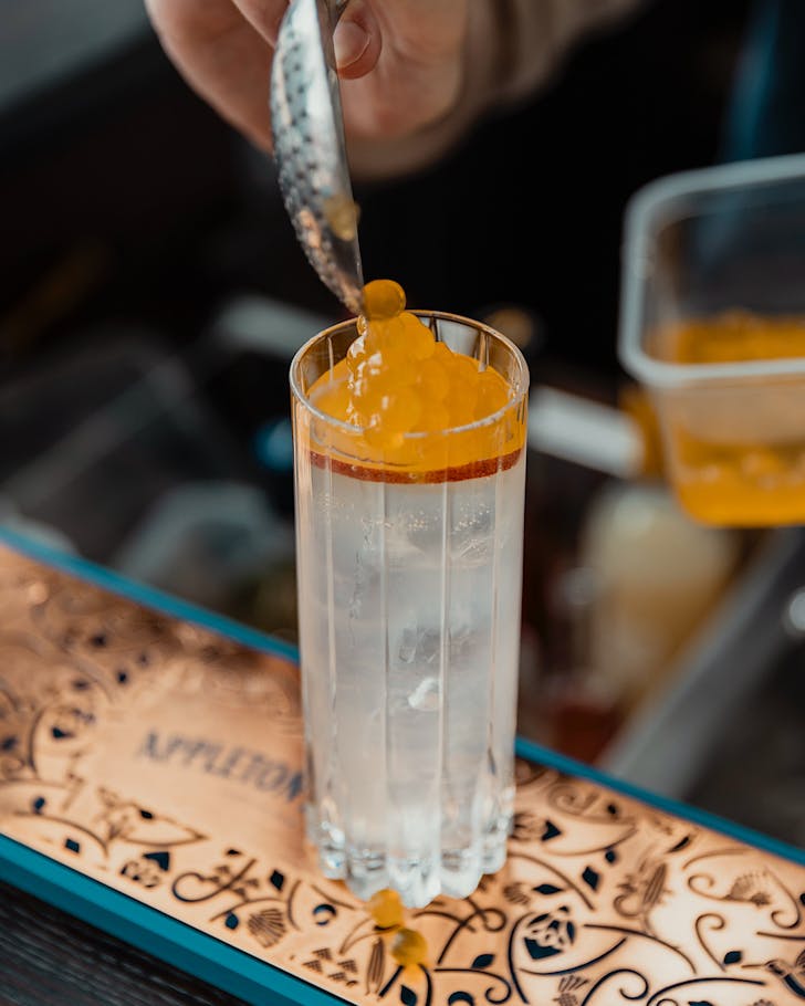 Johnny tops a highball cocktail with peach caviar. 