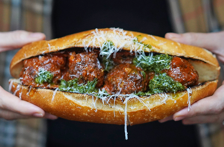 Rocco's meatball sub topped with parmigiano, dripping with red sauce and salsa verde.