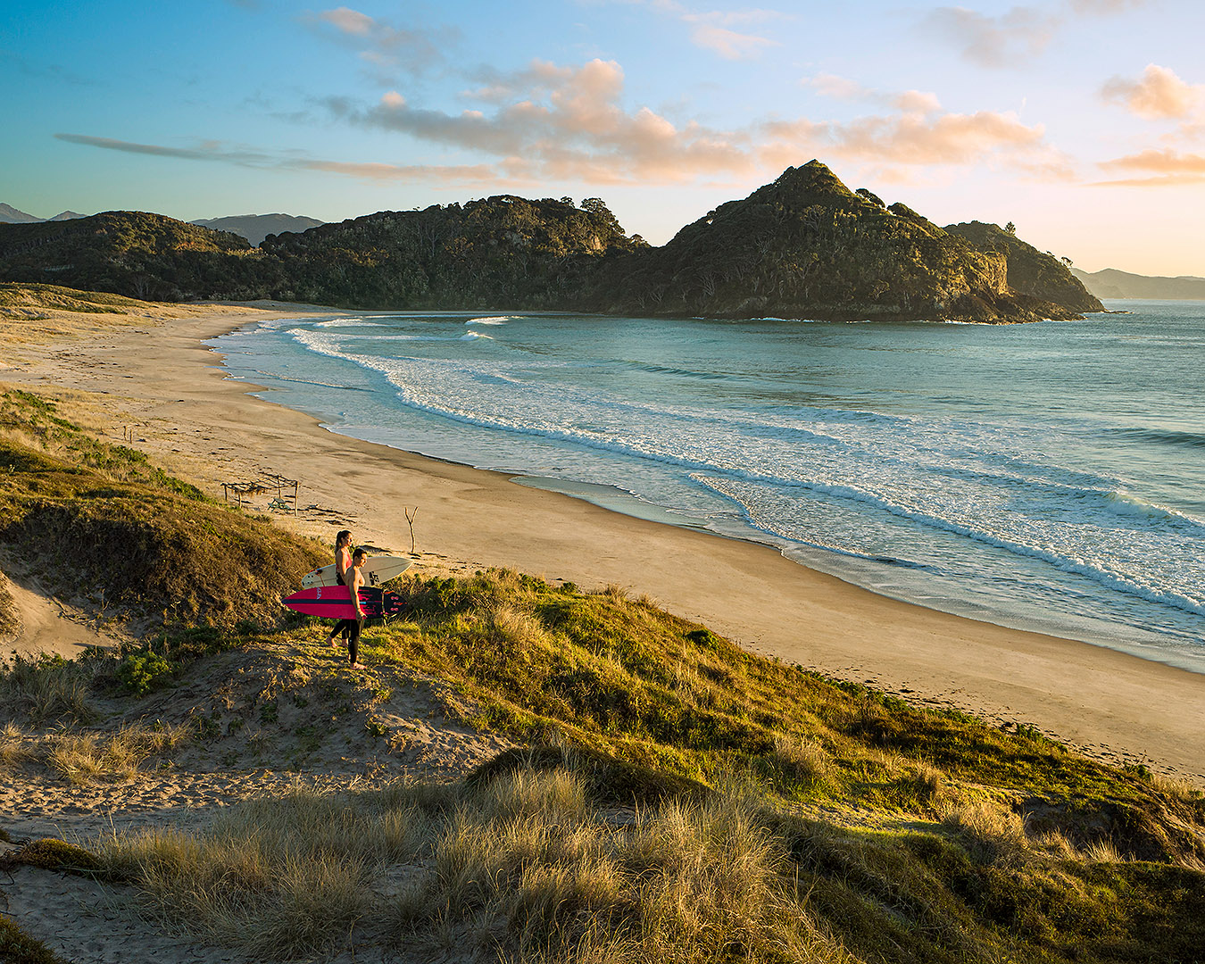 Surfers look out at Medlands Beach on Great Barrier Island.