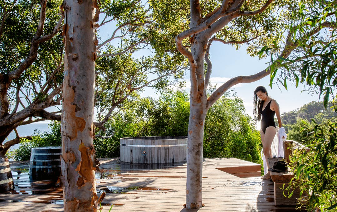 A person in a swimsuit in nature near a bathtub. 