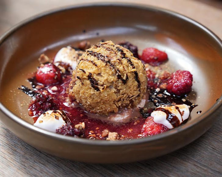 A golden scoop of deep-fried ice cream surrounded by mascerated berries and torched whipped crema. 