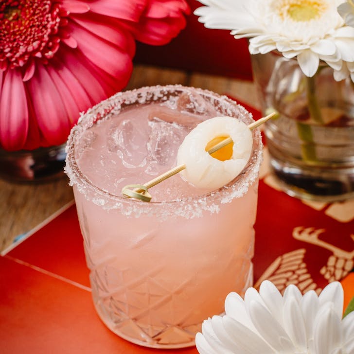 A salt-rimmed margarita topped with a skewered lychee. 