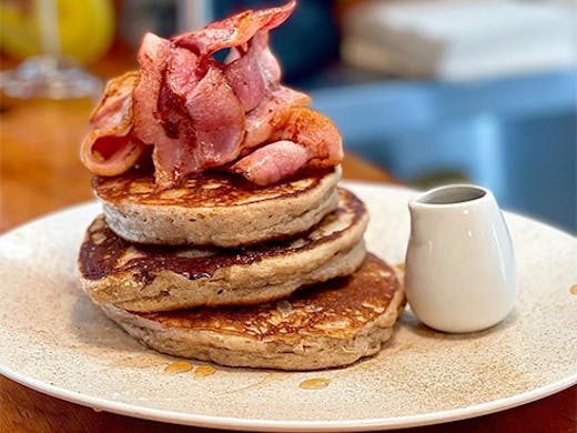 a stack of pancakes topped with bacon