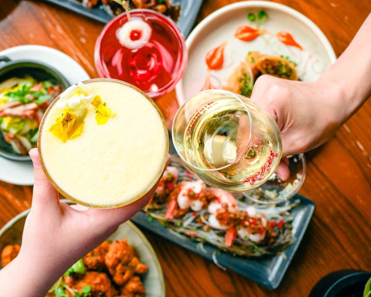 Two people clink drinks at Midnight Shanghai. 