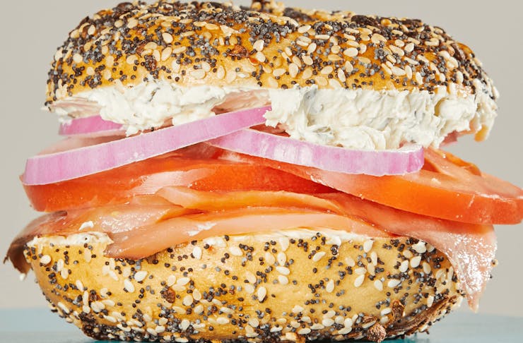 A smoked salmon bagel with tomato and onion. 