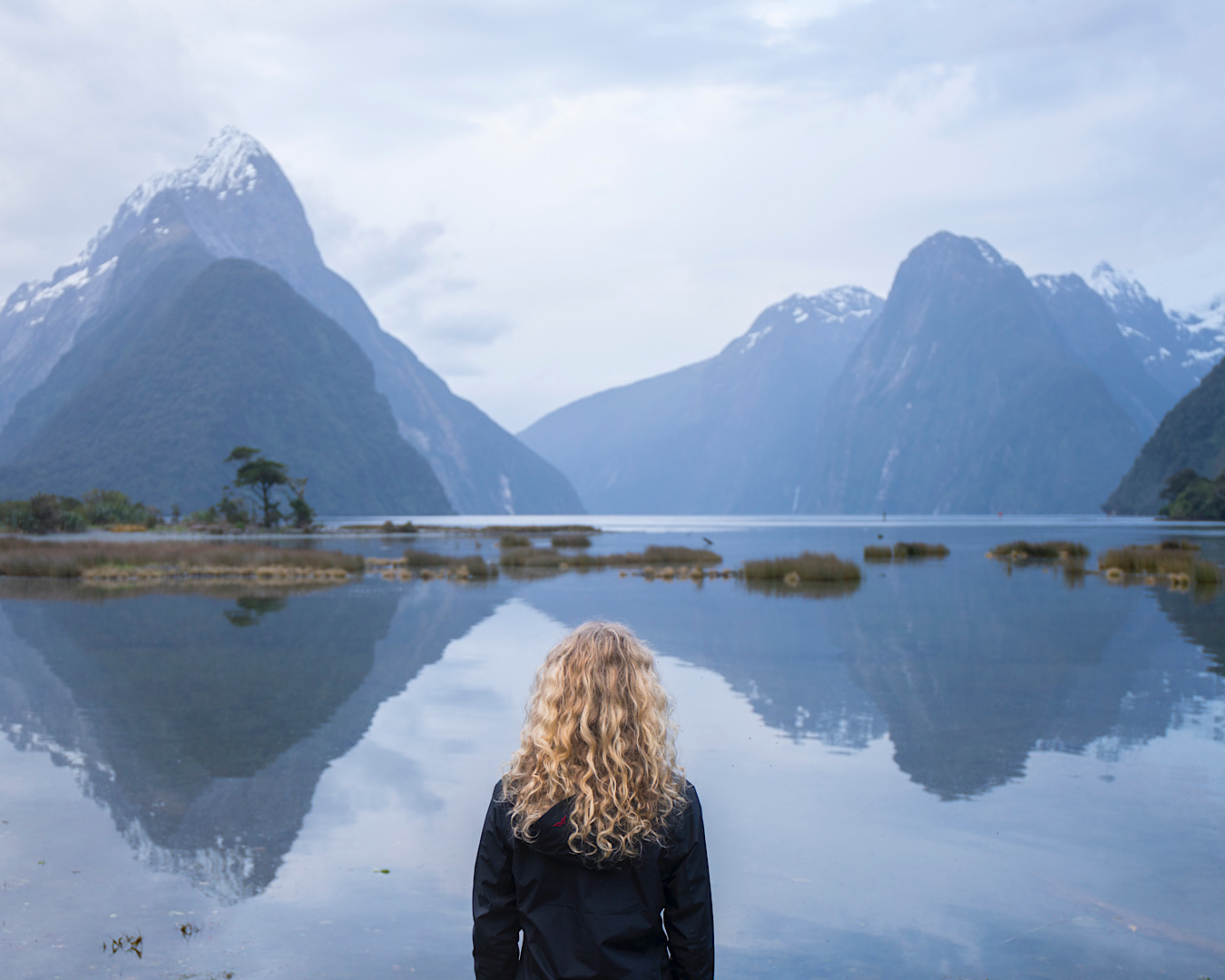 A hiker stands, spell-bound, looking over Milford Sound. 