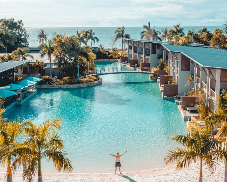 A man stands at the edge of the pool with his hands in the air at Mindil Beach Casino Resort one of the best hotels in Australia