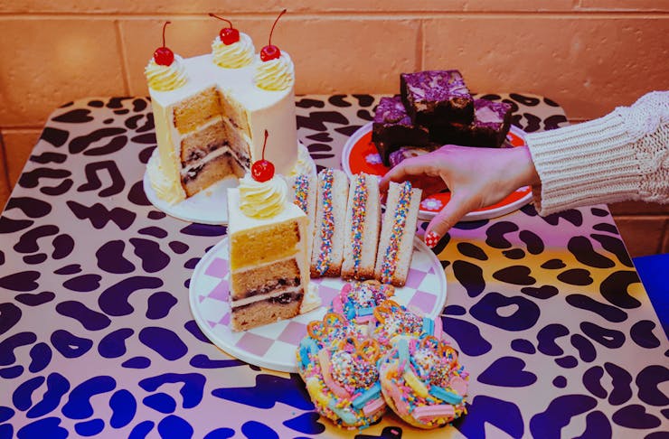 A hand reaching over at a table of desserts. 
