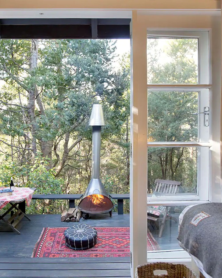 A bedroom looks out onto a deck with an outdoor fireplace.