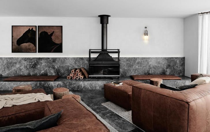 A room with leather couches and a fireplace, a top winery accommodation Victoria.