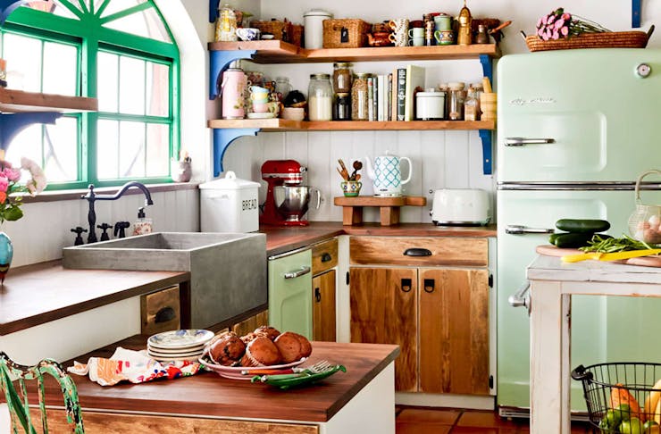 A gorgeous kitchen with vibrant pops of colour, greenery and stacked wooden shelving.