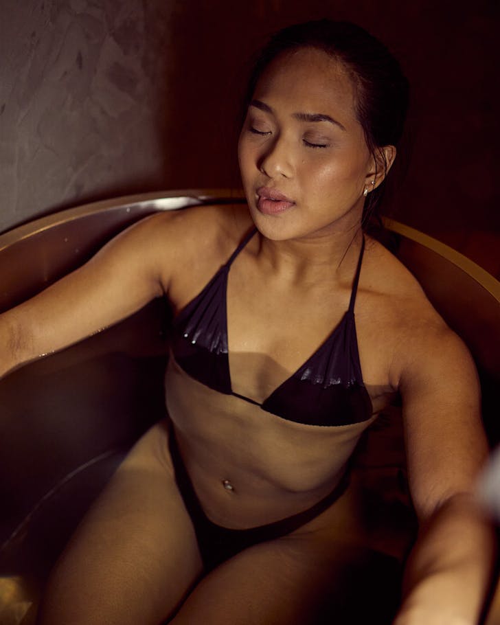 A woman in a bikini sits in an ice bath at Mode. 