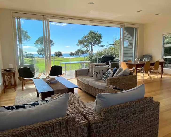 The living space looking out to the water at Modern Retreat In Matarangi one of the best beach house Airbnbs in NZ