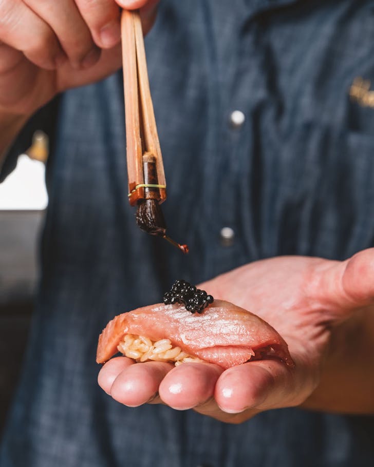preparing a piece of tuna nigiri with caviar for omakase at moku
