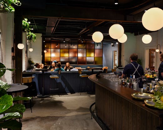 The inside of a bar with plants and pendant lights. 