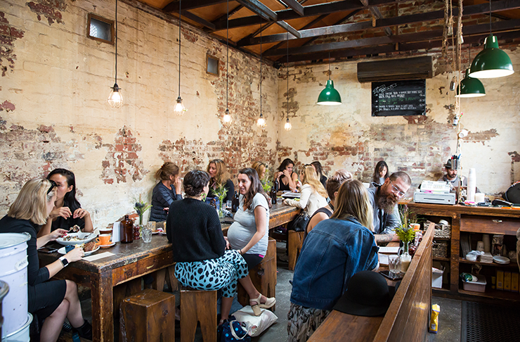 A cafe with exposed bricks and wooden tables, packed with people digging into one of the best breakfasts in Melbourne at Monk Bodhi Dharma.