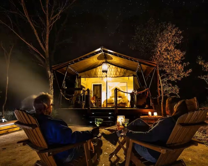 A couple sits around the campfire after dark at Moogie Glamp one of the best romantic getaways Queensland