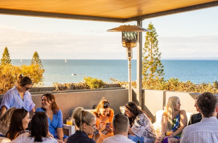 People talking on drinking on a balcony with view of the ocean