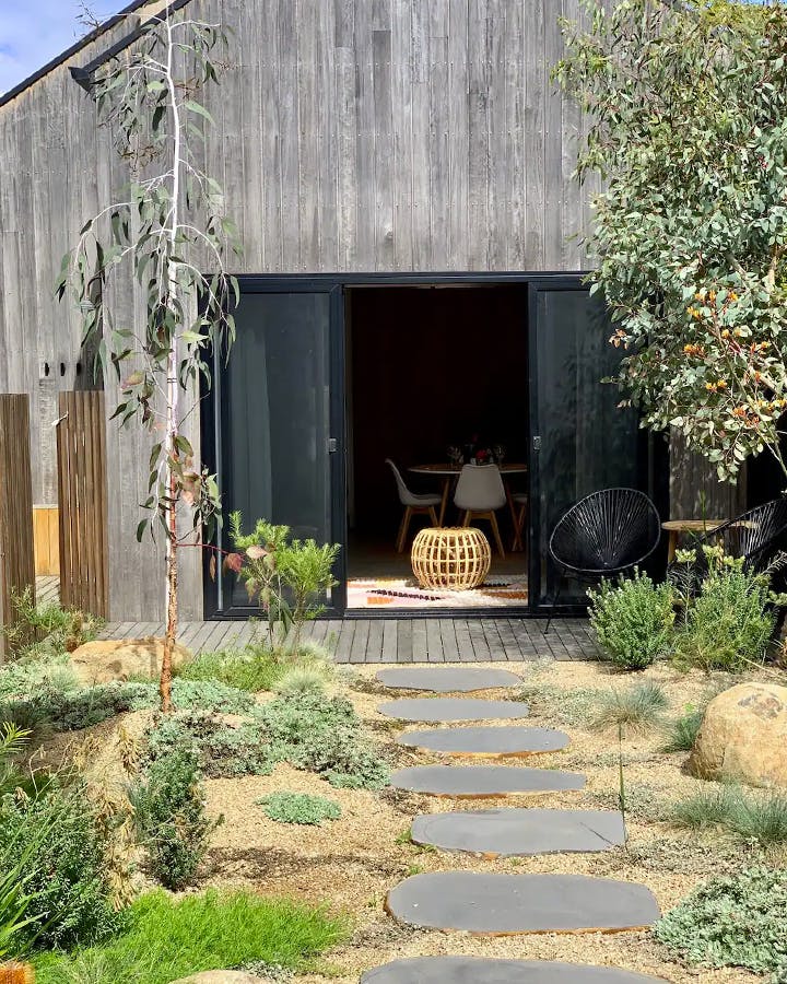 A house with door open and a tidy landscaped garden. 