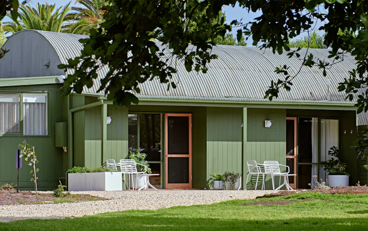 A green hotel with chairs out front.