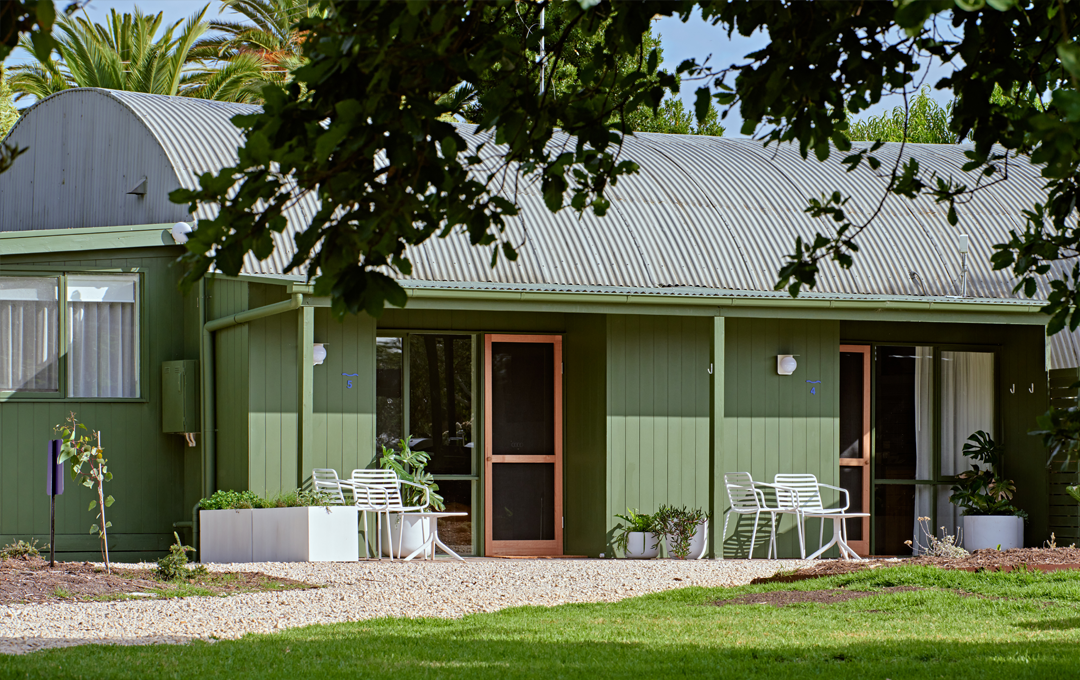 A green hotel with chairs out front.