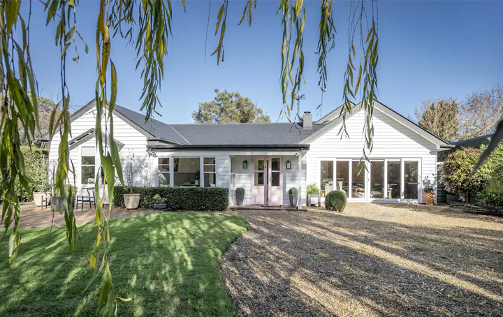A larger white house with a garden and driveway. 