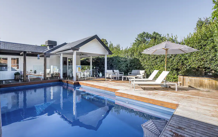 A large backyard with a blue pool and wooden deck, a top Mornington peninsula accommodation.