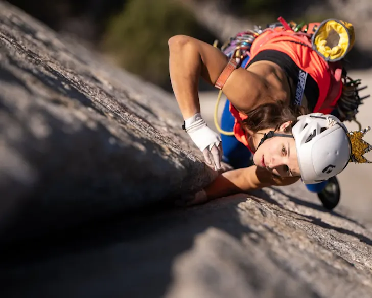 A rock climber scales a sheer rock face. 